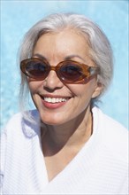 Woman at poolside in bathrobe and sunglasses