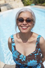 Woman at poolside in bathing suit and sunglasses