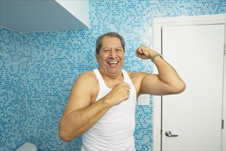 Hispanic man flexing his biceps in bathroom