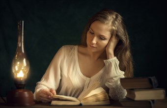 Caucasian woman reading book by candlelight
