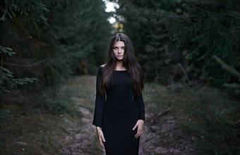 Caucasian woman wearing black dress in forest