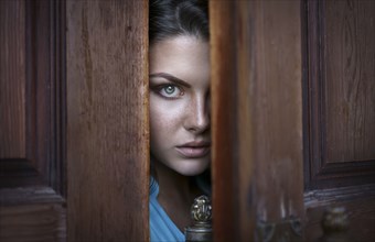 Caucasian woman peeking in doorway