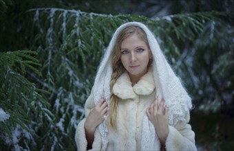 Caucasian woman wearing fur coat in snowy forest