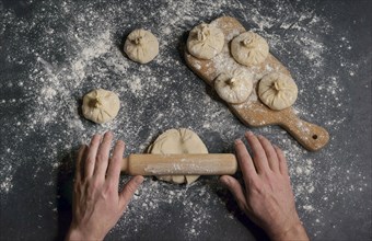 Hands of Caucasian man using rolling pin on dough