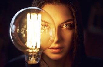Face of Caucasian woman illuminated by energy efficient light bulb