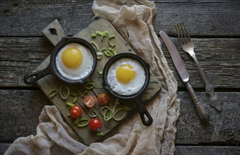 Fried eggs in cast iron pans on cutting board