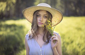 Caucasian woman wearing hat holding wildflowers