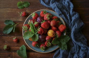 Strawberries and plums on plate