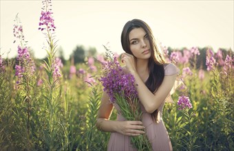 Portrait of Caucasian woman gathering wildflowers in field
