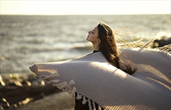 Wind blowing shawl of Caucasian woman at beach