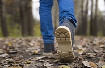 Sole of shoe of Caucasian boy walking on autumn leaves