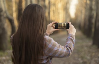 Caucasian woman photographing path with cell phone
