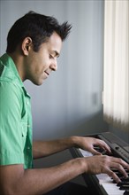 Mixed race man playing electric keyboard