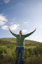 Mixed race man in field with arms outstretched