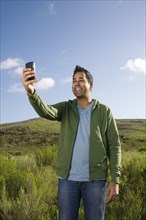 Mixed race man taking photo with cell phone