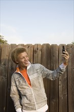 Mixed race boy taking self-portrait with cell phone