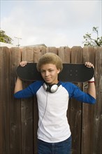 Mixed race boy in headphones holding skateboard