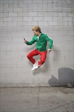 Mixed race boy jumping in mid-air using cell phone