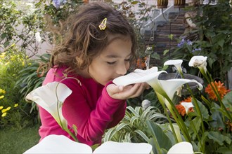 Hispanic girl smelling white flowers in garden