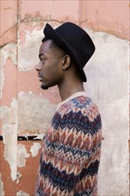 Profile of Black man standing by dilapidated building