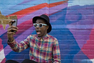 Black man taking selfie near colorful wall