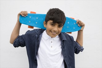 Asian boy holding skateboard