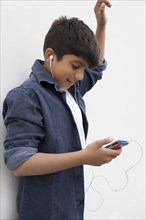 Asian boy listening to earbuds with cell phone