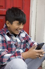 Asian boy using cell phone at door