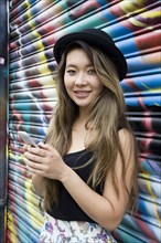 Asian woman using cell phone near graffiti wall