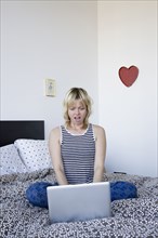 Surprised Caucasian woman using laptop on bed