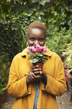 Portrait of smiling Black woman smelling flowers