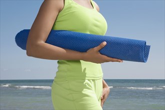 Hispanic woman holding yoga mat