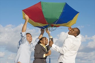 Multi-ethnic businesspeople opening beach umbrella