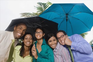 Hispanic businesspeople standing under umbrellas