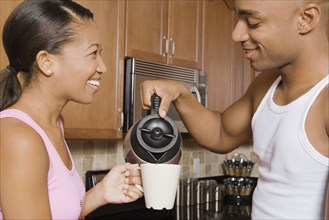 African man pouring coffee for wife