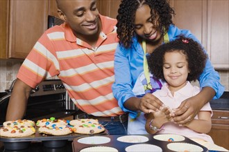 African parents and daughter making cupcakes