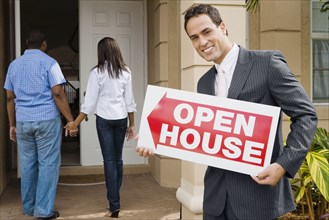 Hispanic real estate agent holding Open House sign