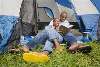 African couple reading at campsite