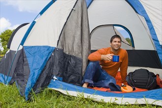 Hispanic man drinking coffee in tent