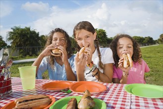 Hispanic girls eating at picnic table