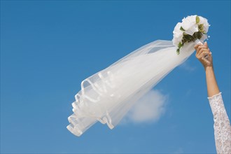 Hispanic bride holding bouquet in air