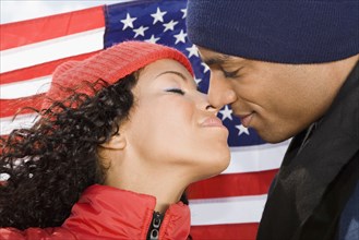 Multi-ethnic couple kissing in front of American flag