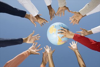 Multi-ethnic hands reaching for globe ball