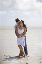 Hispanic couple hugging at beach