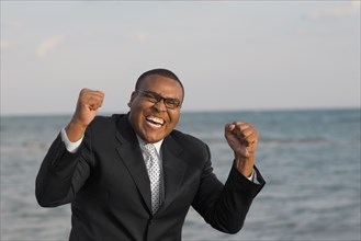 African businessman cheering in front of water
