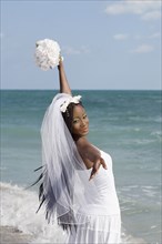 African bride looking over shoulder at beach