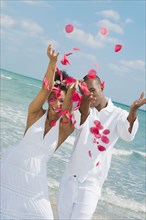 Multi-ethnic couple throwing flower petals in air