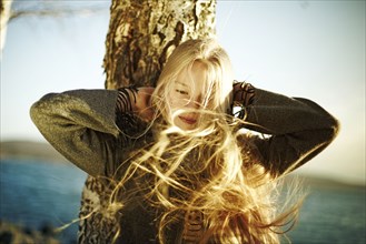 Caucasian girl's hair being blown by the wind near ocean
