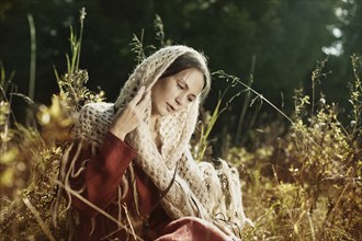 Caucasian woman in scarf sitting in field