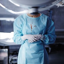 Caucasian surgeon with blood on gown in operating room